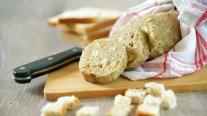 Aufgeschnittener Serviettenknödel auf einem Brett in ein Tuch eingewickelt