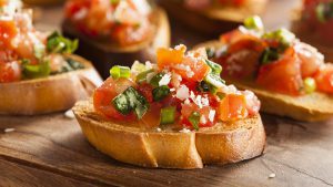 Bruschetta: Mehrere Brotscheiben mit Bruschetta, bestehend aus Tomaten und Basilikum