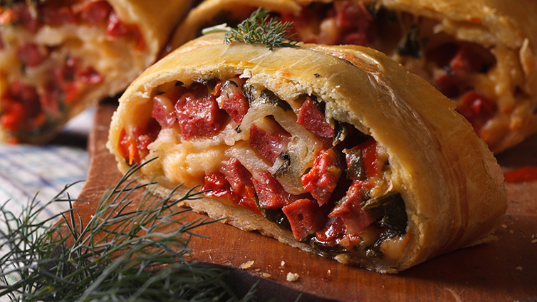 Strudel mit Schinken und Käse auf Holzbrett