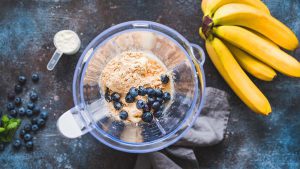 Beeren, Proteinpulver und Bananen im Mixer