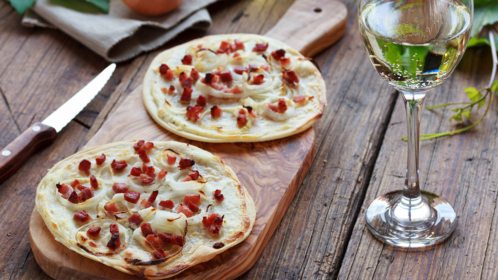 Mini Flammkuchen auf Holzbrett zu Wein