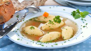 Grießnockerlsuppe im Teller mit Brötchen