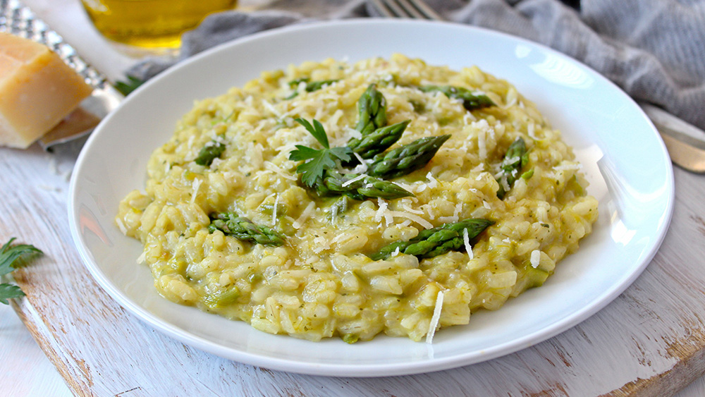 Spargelrisotto mit grünem Spargel ist auf einem weißen Teller angerichtet.