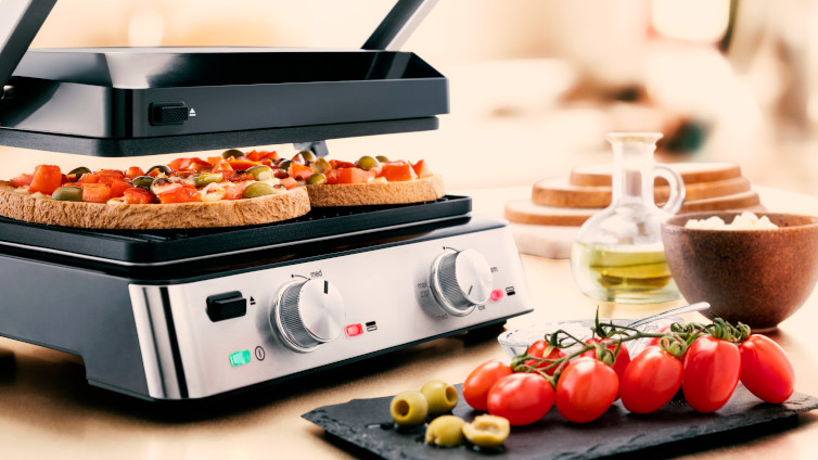 Braun Multigrill 7 mit Bruschetta neben Tomaten und Oliven.