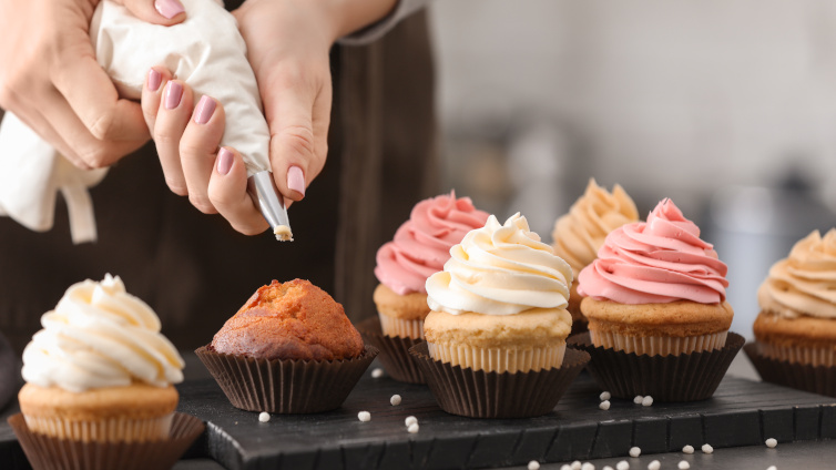 Person spritzt Frosting auf Cupcakes.