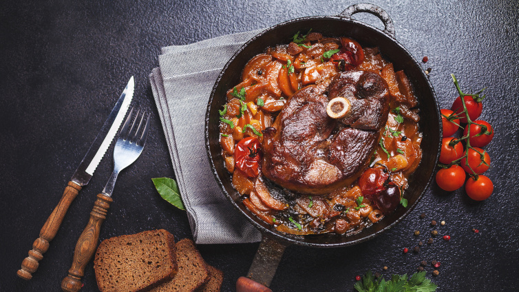 Ossobuco alla milanese in einer gusseisernen Pfanne mit Beilage.